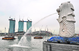 Tourists take a river tour along the waterfront next to the Merlion 