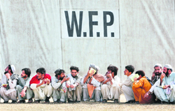 Men sit in a queue at one of the food distribution points under the UNs World Food Programme located in Pakistans NWFP