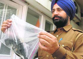 A police officer shows the .32 bore revolver with which Singh reportedly shot himself
