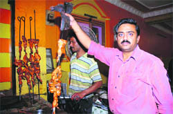 The owner of Sham Da Dhaba, Vijay Mehra, displays a freshly cooked tandoori chicken. The dhaba has been operational for the past 60 years at Satwari. 