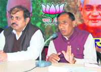 Uttarakhand BJP chief Bisan Singh Chufal (R) addresses mediapersons in Dehradun
