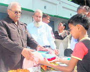 Assembly Speaker Harbans Kapoor distributes school uniforms to students in Dehradun on Saturday.