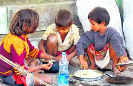 Three ragpickers have their meal on a road pavement in Dehradun on Tuesday