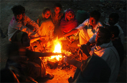 A group of migrant labourers sits around a bonfire in Gurgaon