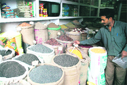 A shopkeeper in Jammus Kanak Mandi changes price tags on grocery items after an increase in their rates