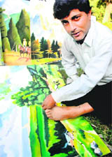 Uttam, a physically challenged artist, displays his painting skills during a press conference in Chandigarh on Saturday.