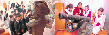Schoolchildren look at an old sculpture in the government museum in the Mandi Mubarak complex during the ongoing World Heritage Week in Jammu on Saturday; and (right) girls have a close look at a historical cannon.