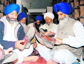 Jagdish Singh Jhinda (right), president, HSGPC (ad-hoc) along with other members of the body cleans shoes at Golden Temple in Amritsar on Sunday.