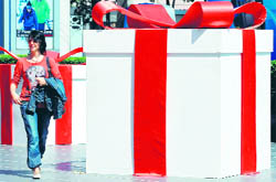 A tourist walks past a giant gift box displayed for the upcoming Christmas festival at a shopping mall in Bangkok on Monday