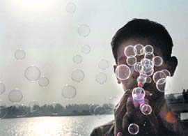 A boy joyfully blows out bubbles on the banks of Brahma Sarovar in Kurukshetra.