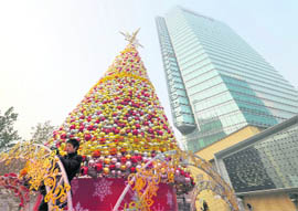 A worker places ornaments onto a huge Christmas tree outside a shopping mall in Beijing on Thursday. China's economy could grow by over 10 per cent in the fourth quarter of 2009 spurred by massive investment and rising consumption, the state press said, citing a top government think tank