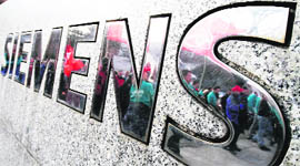 Employees of German industrial group Siemens are reflected in the company logo in Berlin. On Thursday several thousand employees went on protest against the company's job policy in the German capital