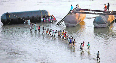 Labourers pull a pontoon as they construct construct a temporary bridge for Magh Mela festival at the Ganga river in Allahabad.