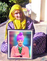 Brahmi Devi posing with the picture of her late husband Naik Kirpa Ram in her village-Bhapral.