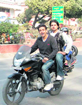 Two boys ride a motorcycle without helmets in Dehradun.
