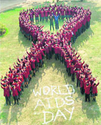 Students form a red ribbon a day before World AIDS Day on December 1 in Faridabad on Monday