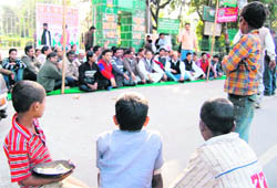 Four boys, who sell petty things on the roadside, watch Congress Labour Cell workers stage a dharna against child labour in Dehradun on Wednesday.