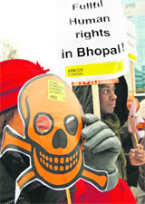 25 years later, Amnesty International activists wear masks representing victims of the Bhopal gas tragedy at a demonstration outside the  European HQ of Dow Chemicals in Brussels on Wednesday.