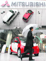 A man passes by Mitsubishi Motors Corp's headquarters in Tokyo on Thursday. Top management at the Mitsubishi group are open to PSA Peugeot Citroen's taking a more than 50 per cent stake in Mitsubishi Motors Corp, if conditions are right, the Nikkei business daily said in its evening edition on Thursday