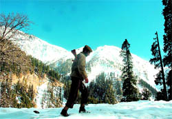 A security man patrols the snow-covered Mughal Road at Chjatta Pani in Poonch.