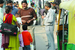 An autorickshaw driver bargains for a high price with potential customers at the New Delhi railway station.