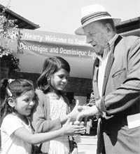 French author Dominique Lapierre shakes hands with children of victims of the gas tragedy during his visit to Sambhawna Trust Clinic to mark the 25th anniversary of the Bhopal gas tragedy in Bhopal