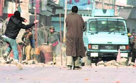 A youth pelts security personnel with stones during a protest over the attack on Hurriyat leader Fazal-ul Haq Qureshi in Srinagar