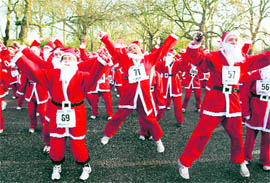 Runners dressed as Santa Claus warm up to seasonal music before the London Santa Run in Battersea Park, London on Sunday