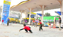 Children play cricket outside a petrol station after all public and private establishments closed down following the imposition of curfew in Ludhiana on Sunday.