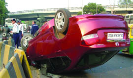 A car overturns near the Oberoi Hotel in New Delhi on Monday.