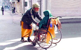 An old mad takes his ill wife on a wheelchair in curfew after he failed to find any mode of conveyance to take her home.