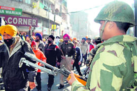 A BSF jawan stands guard while activists of various Sikh organisations participate in a march in Amritsar during a bandh on Monday.