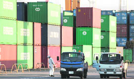 A worker walks in a container area at a port in Tokyo on Tuesday. Japan's government agreed on a 7.2 trillion yen ($81 billion) stimulus package on Tuesday, aiming to prevent the economy from tipping back into recession as deflation persists and a strong yen threatens exports.