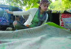 A Green Peace activist stitches banners carrying environmental messages in New Delhi on Tuesday.