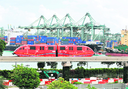 A monorail train travelling from Sentosa Island resort passes the Brani container terminal in Singapore