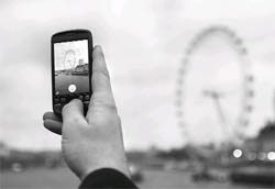A Google employee holds up a mobile phone to demonstrate how the new Goggles application recognises the London Eye as seen from Westminster Bridge in central London December 7, 2009. The new application recognises millions of objects and landmarks all over the world after they have been photographed on a mobile phone.