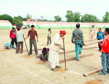 Workers dig up the ground of the MA Stadium in Jammu to make arrangements for a musical event.