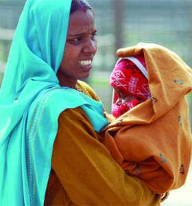 A woman covers her child to save from the cold wind on Sunday morning in New Delhi