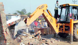 A JCB machine razes structures.