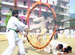 A karate player passes through a fire ring at the founders day celebrations of GRD Academy at Rajpur near Dehradun on Monday.