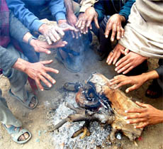 Poor labourers try to keep the chill away.