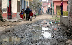 Residents cross a water filled and muddy road in Ward No 13 in Amritsar.