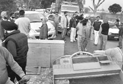 A shopkeeper blocks a road during a demolition drive by GMADA near Swara village in Mohali on Wednesday.
