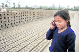A daughter of a brick-kiln labourer talks on a mobile phone near Shimla Bypass Road in Dehradun on Thursday.