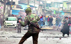 A security man under attack from a stone-pelting mob.