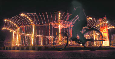 A man cycles passed a roundabout illuminated to welcome the Jagannath rath yatra in Ludhiana.
