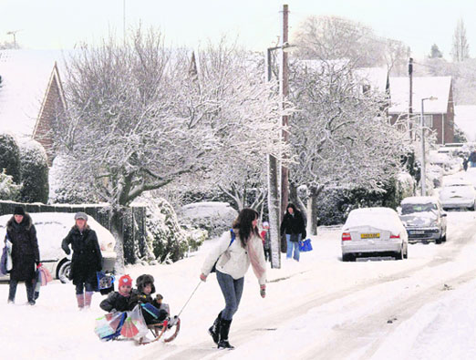 A woman takes her children to school by sledge after heavy snowfall in Rayleigh, southern England, on Friday. Commuters and air passengers faced delays and disruption across much of Britain with the forecaster saying more was on the way. 