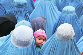 An infant looks on as women wait for distribution of food by a German humanitarian organisation among Afghan residents in downtown Kunduz on Saturday.