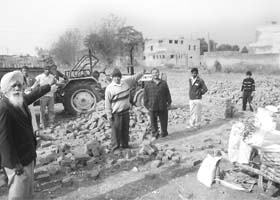 Residents point towards the common wall of the Government Senior Secondary School, Tripri, and the marriage palace