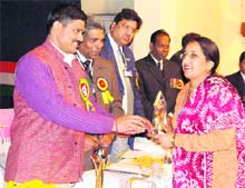 Minister of Sports and Civil Defence Rajinder Singh Bhandari presents a prize to a civil defence warden in Dehradun on Sunday.